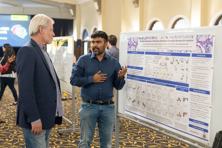 A graduate student presents their research to Tom Jakobsen at the 2025 Jakobsen Conference.